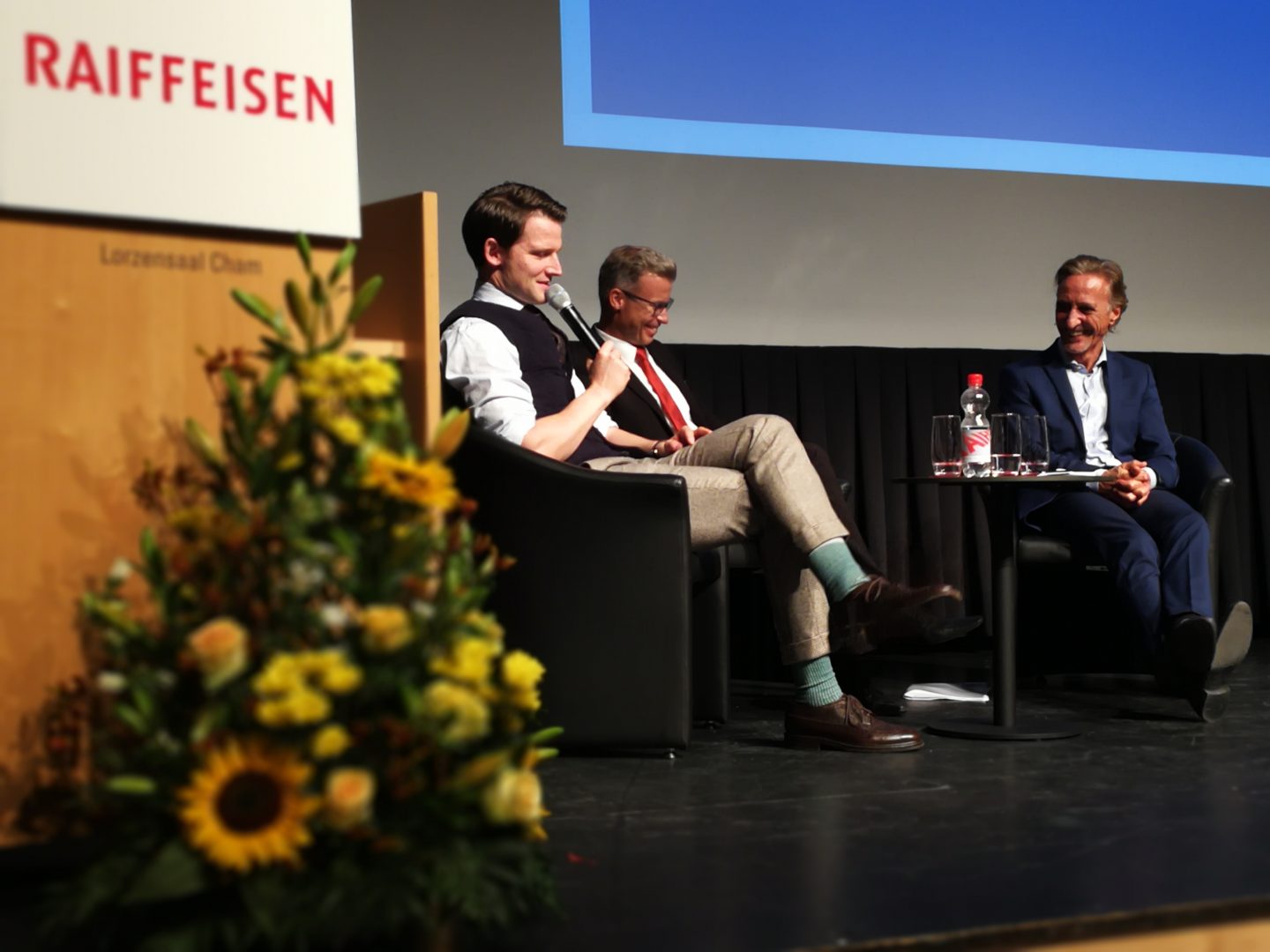 Links: Comedian Fabian Unteregger, Mitte Moderator und Bankleitungsmitglied Pius Vogel und rechts Raiffeisen Chef-Ökonom Martin Neff
