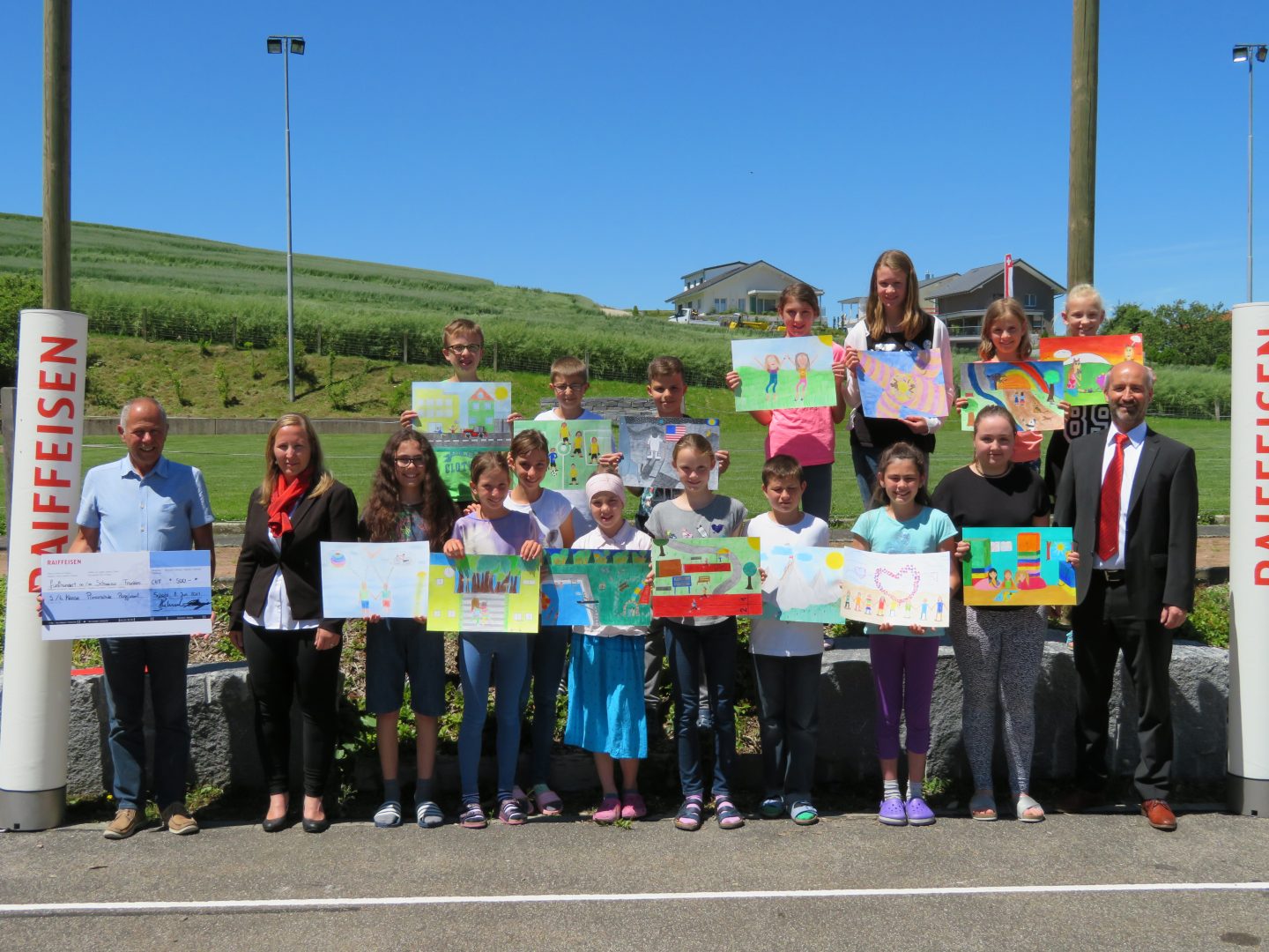 Herr Daniel Chappuis und Frau Nadjne Osifo-Peter übergeben den Check an Herr Peter Rütter und seine Klasse.