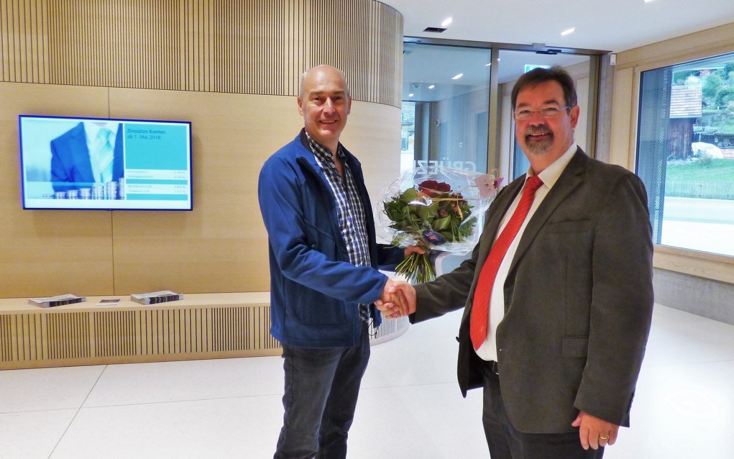 Ernst Zwingli übergibt dem ersten Kunden einen Blumenstrauss