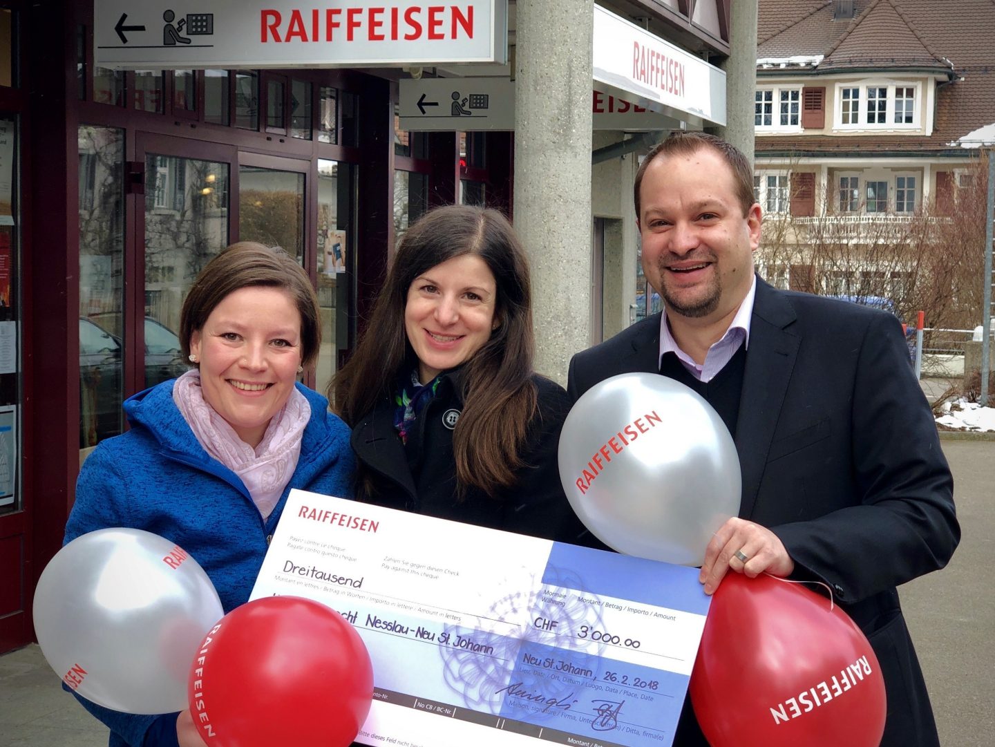 Bankleitungsmitglied Benjie Egloff bei der Checkübergabe an Marianne Wright und Désirée Bachofen