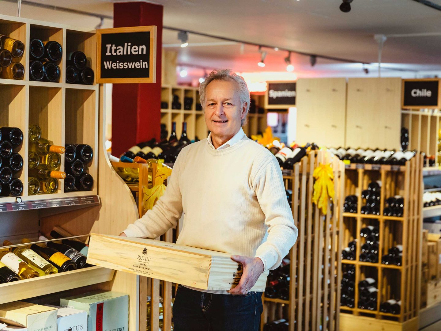 Roland Kaufmann mit einer Holzkiste in der Wein transportiert wird.