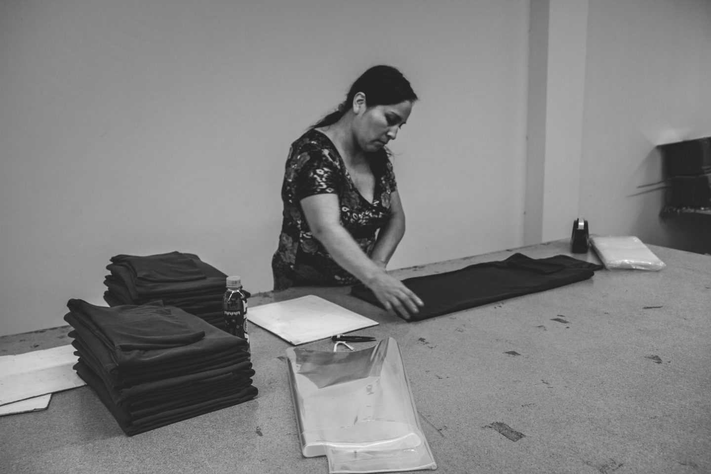 Une femme en train de plier des t-shirts prêts à l’envoi.