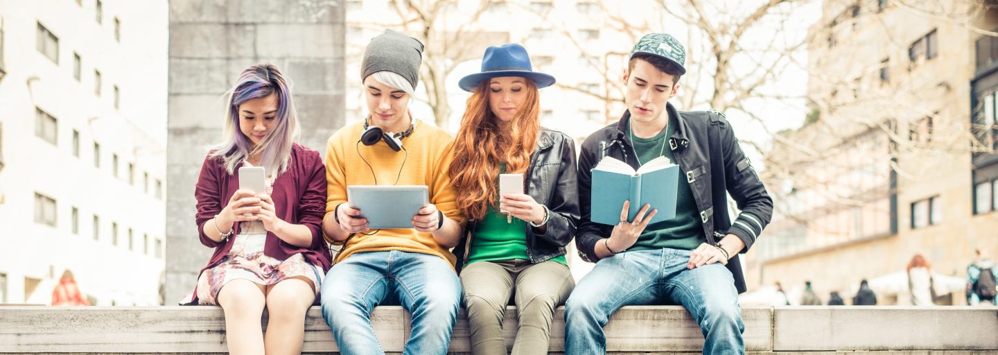 4 Jugendliche sitzen auf einer Mauer